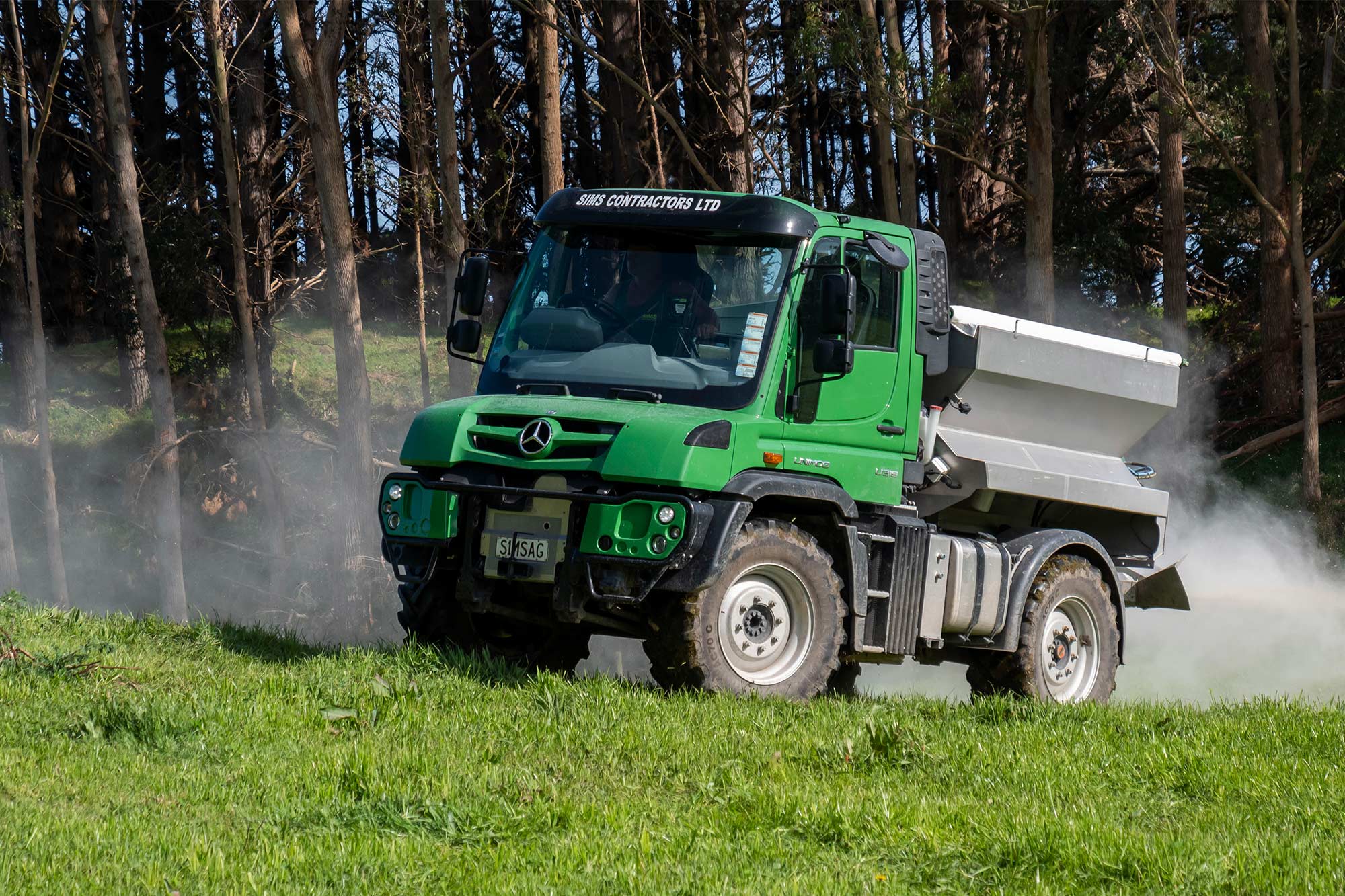 A Mercedes-Benz Unimog spreads product on the ground 