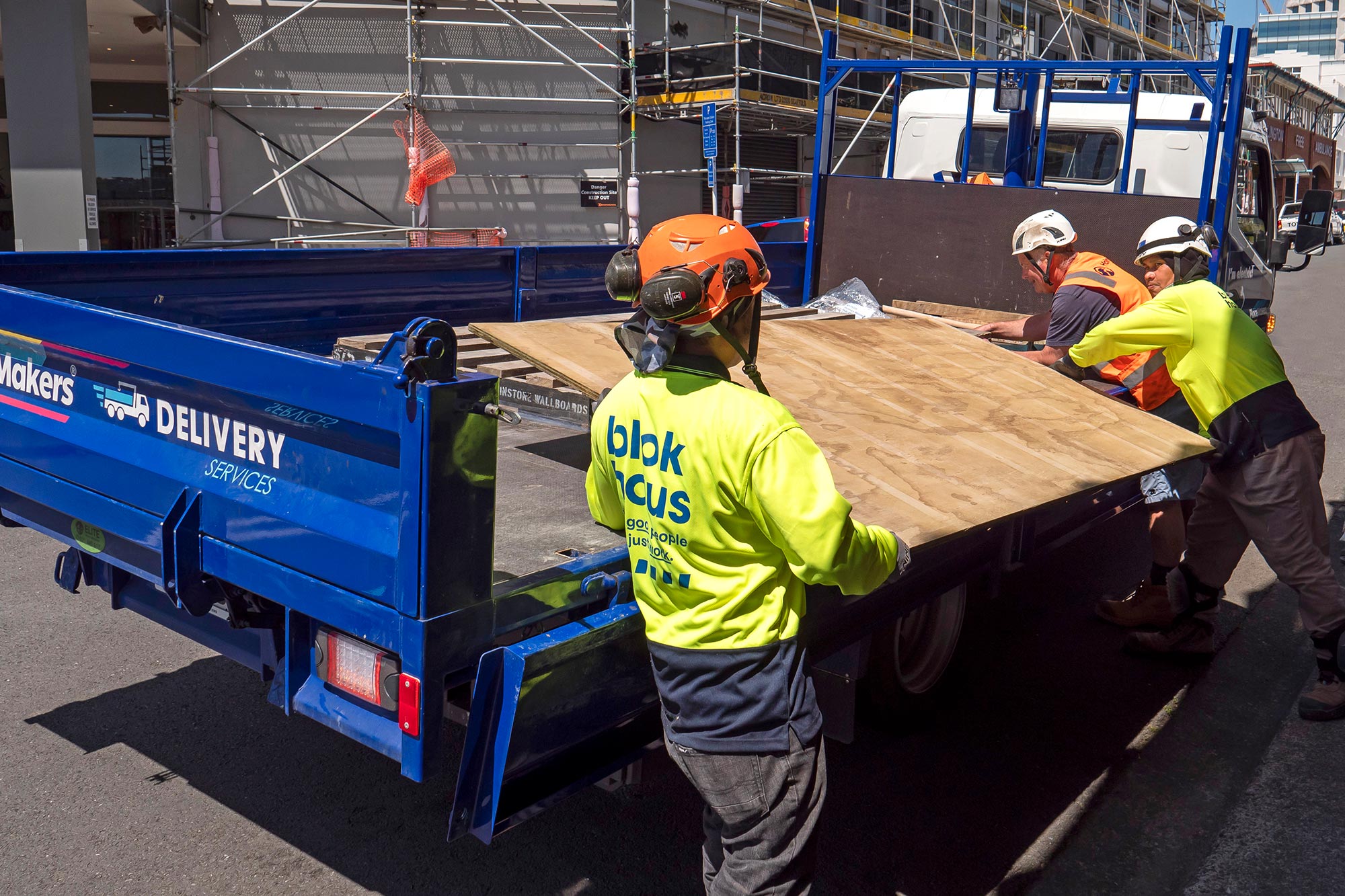 A FUSO eCanter is unloaded on a building site by three workers 